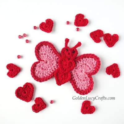 Crochet butterfly applique made from hearts, small hearts and beads around it.