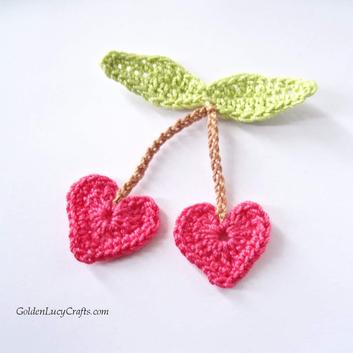 Crochet pink heart-shaped cherry applique.