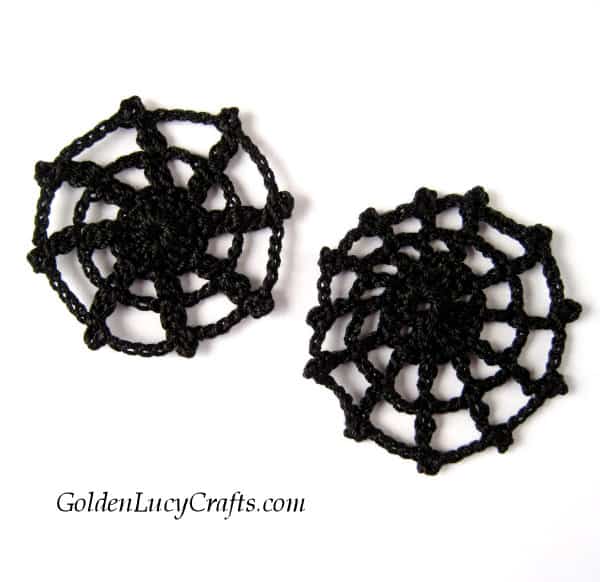 Two black crocheted spider web appliques.