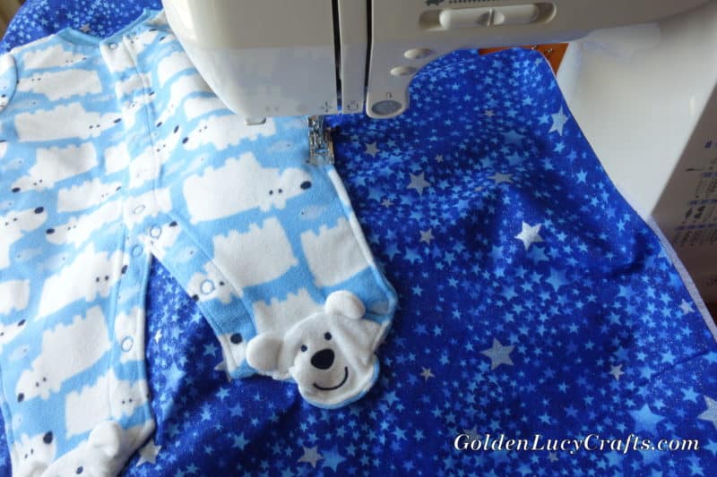 Process shot of making baby quilt sewing clothing piece onto the fabric.