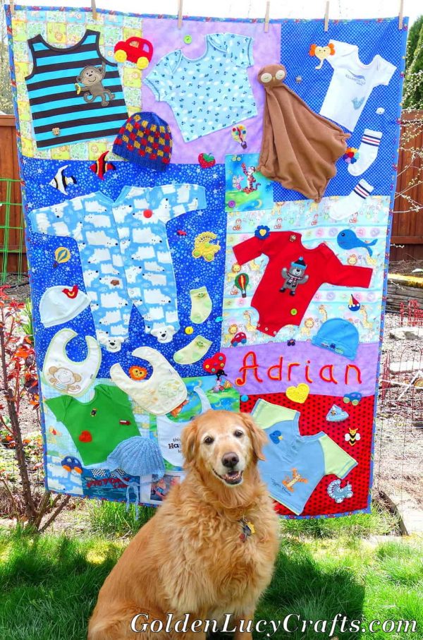 Baby clothes memory quilt hanging on the clothes line, dog sitting in front of it.