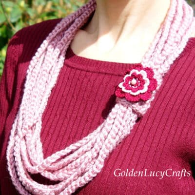 Crocheted pink scarf embellished with crocheted dark red rose.