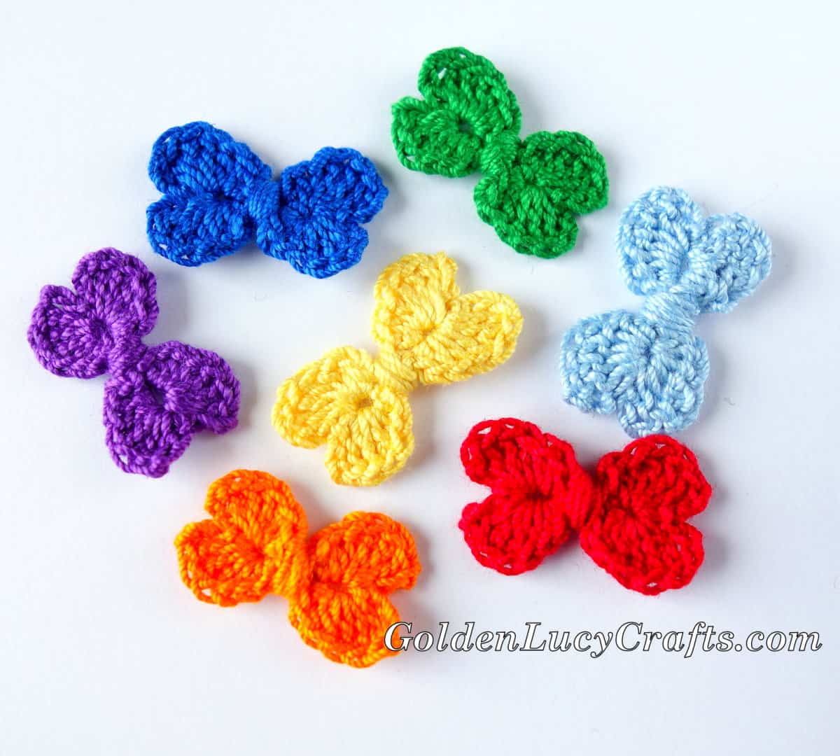 Seven crocheted small bows in colors of rainbow.