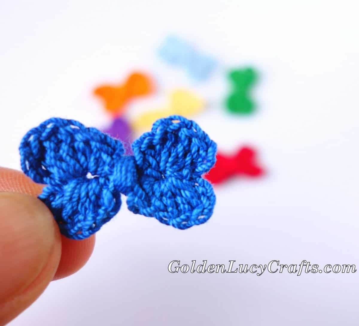 Crochet small bow held by fingertips.