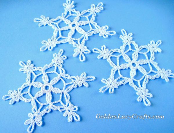 Three white crocheted snowflakes on the blue background.