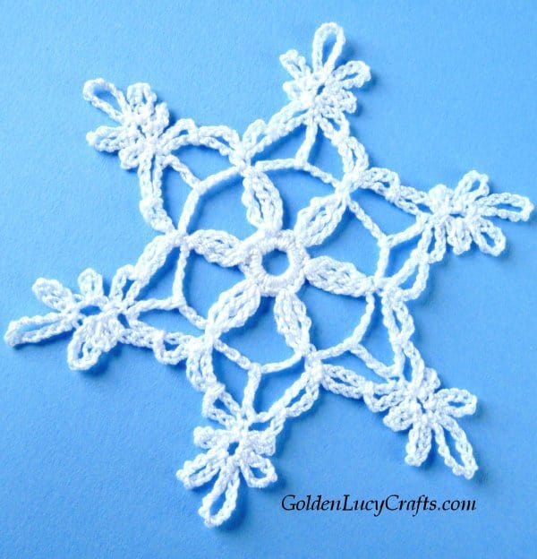 Crocheted white snowflake on blue background.