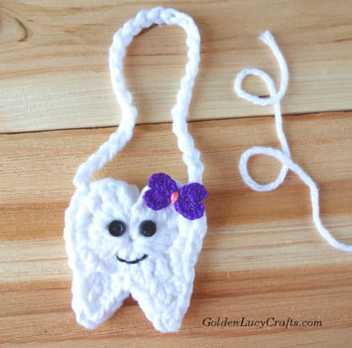 Crocheted tooth with eyes, smile and bow.