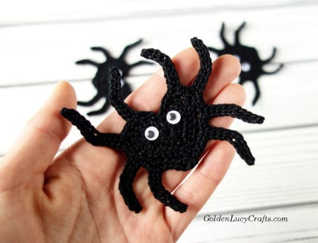Crochet spider applique in the palm of a hand.