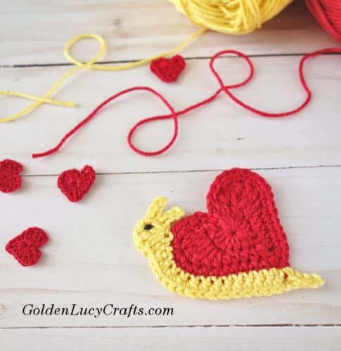 Crocheted snail applique with heart-shaped shell.