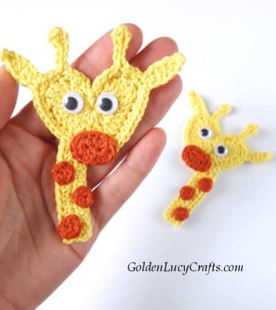 Crochet heart giraffe in the palm of a hand.
