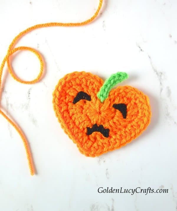 Crochet heart pumpkin with sad face.