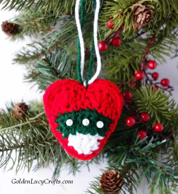 Crochet Christmas heart ornament hanging on Christmas tree.