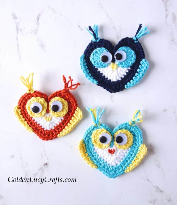 Three appliques crochet heart owls with googly eyes.
