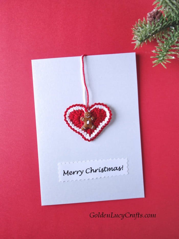 DIY Christmas card embellished with crocheted heart with gingerbread man button on it, text saying Merry Christmas.