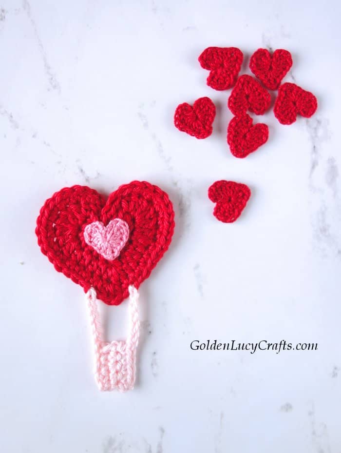 Red crochet heart hot air balloon applique and bunch of hearts next to it.