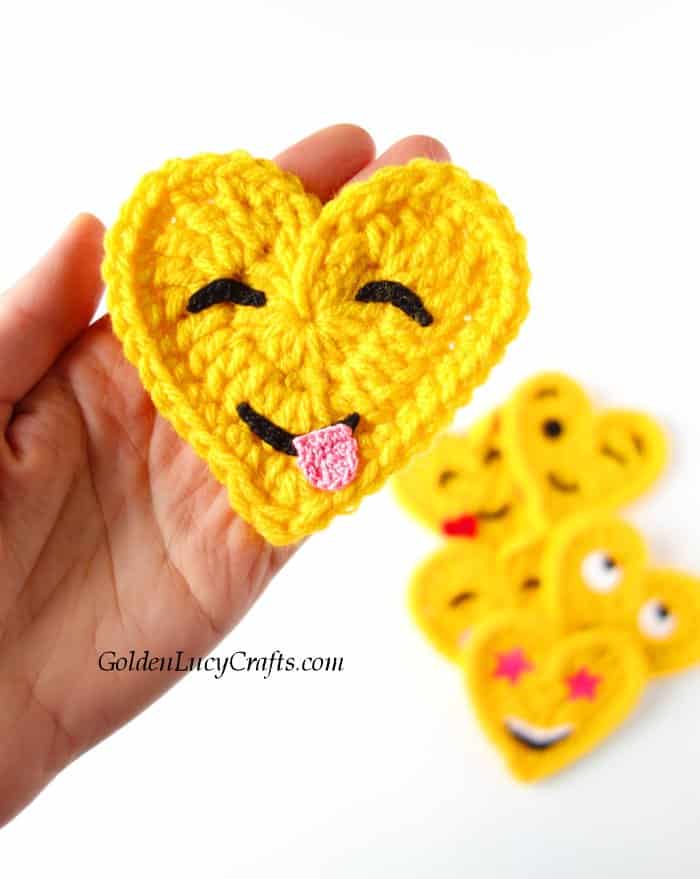 Crochet heart emoji in the palm of a hand.