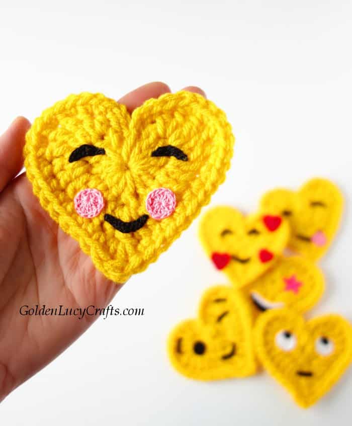 Crochet happy face emoji in the palm of a hand.