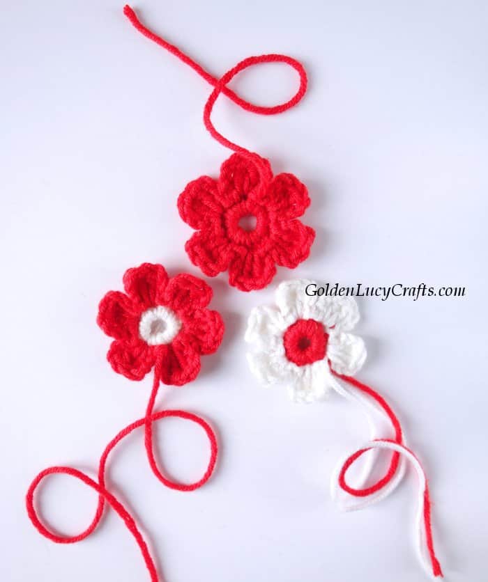 Three crocheted red and white flowers.