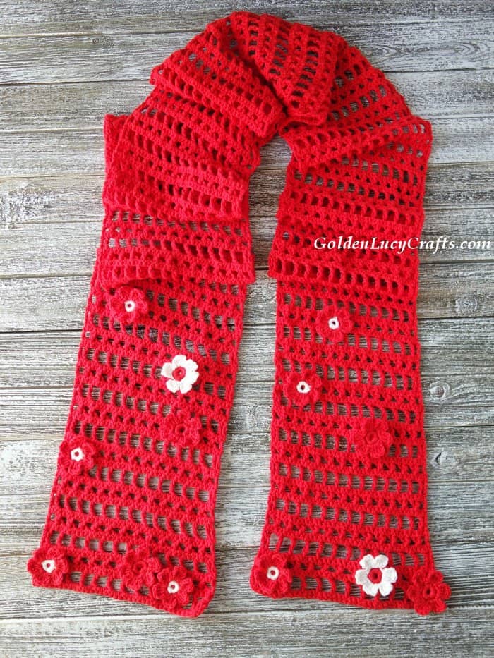 Crocheted red scarf on wooden surface.