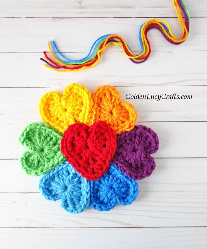 Crocheted flower with heart-shaped petals in colors of the rainbow.