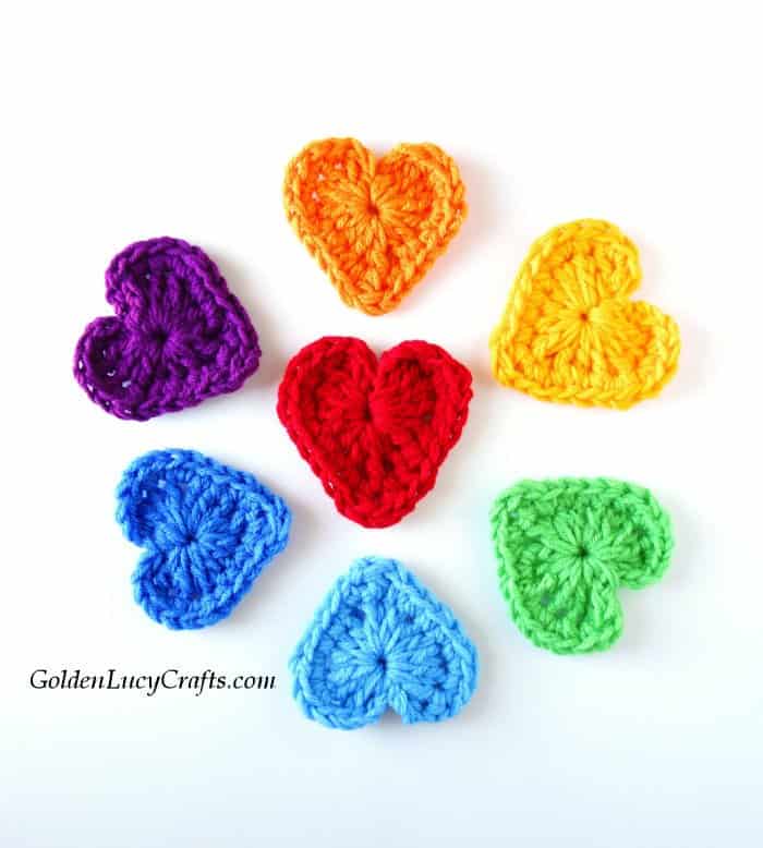 Crochet hearts in colors of the rainbow arranged in a flower shape.