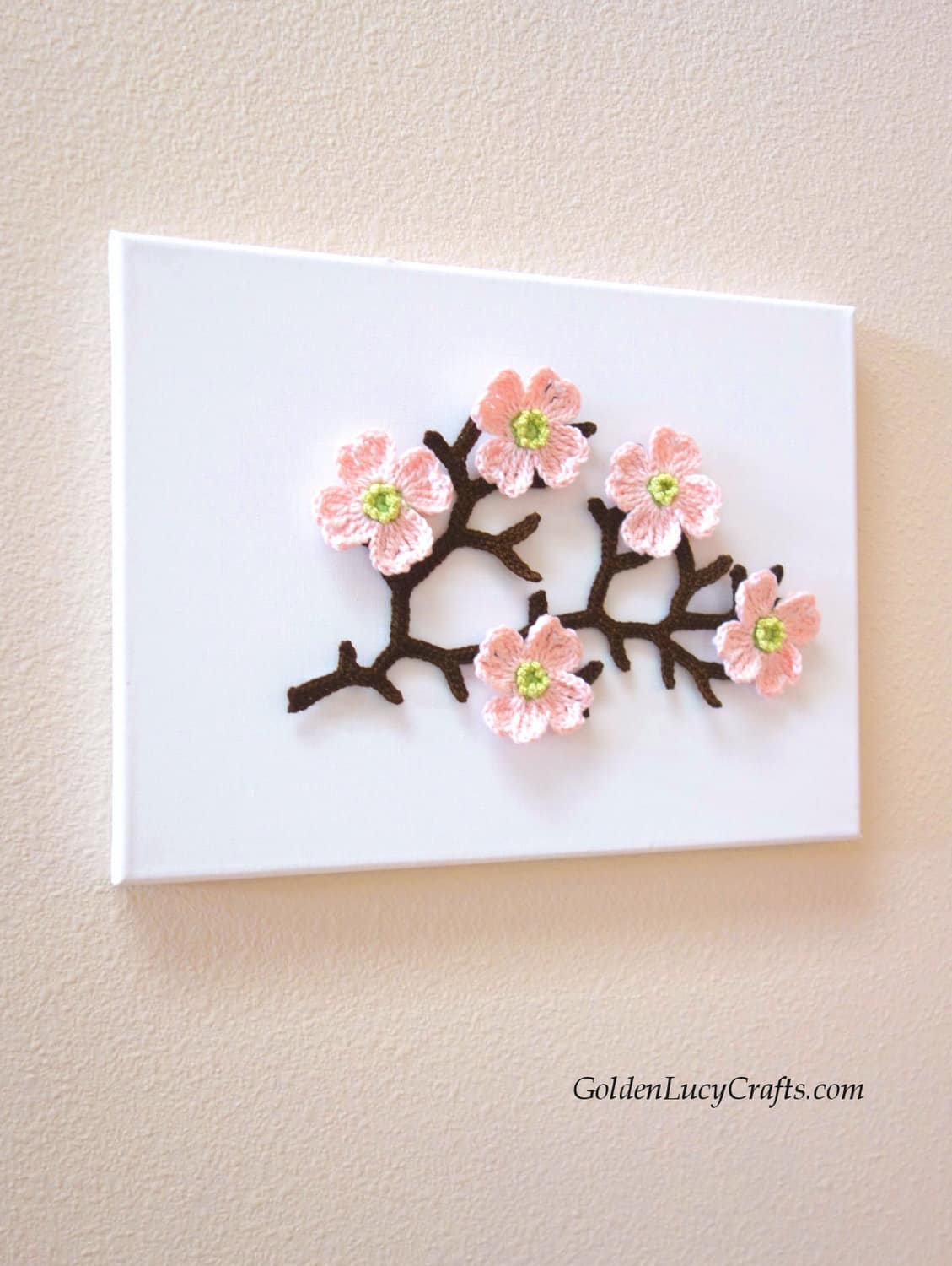 Crochet branch with dogwood flowers on canvas.