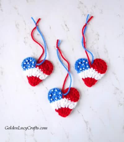 Three crocheted hearts in red, white and blue colors.