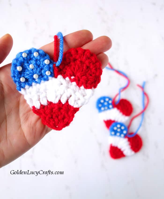 Crochet patriotic heart in the palm of a hand.