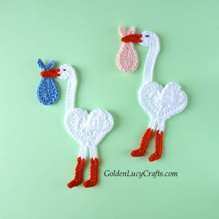 Two crocheted stork appliques.