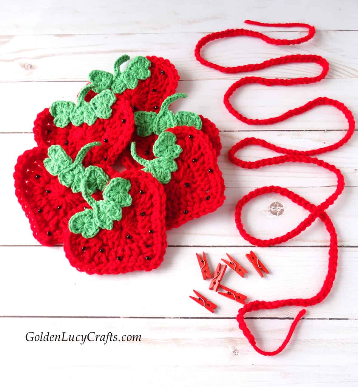 Crocheted strawberry appliques, string and small craft clothespins.