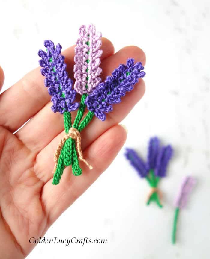 Crochet lavender applique in the palm of a hand.