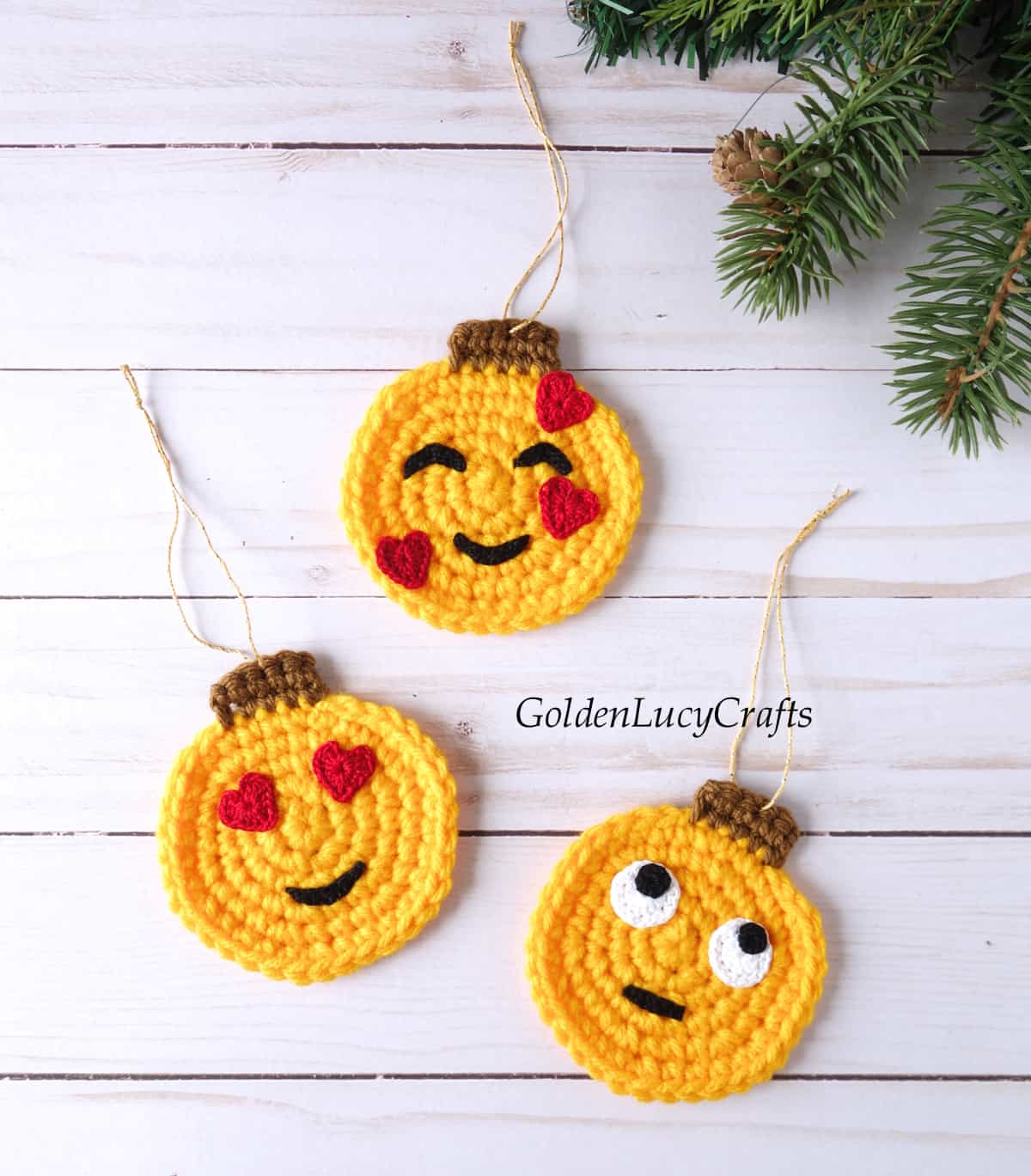 Three crochet emoji Christmas ornaments laying flat on the flat surface.