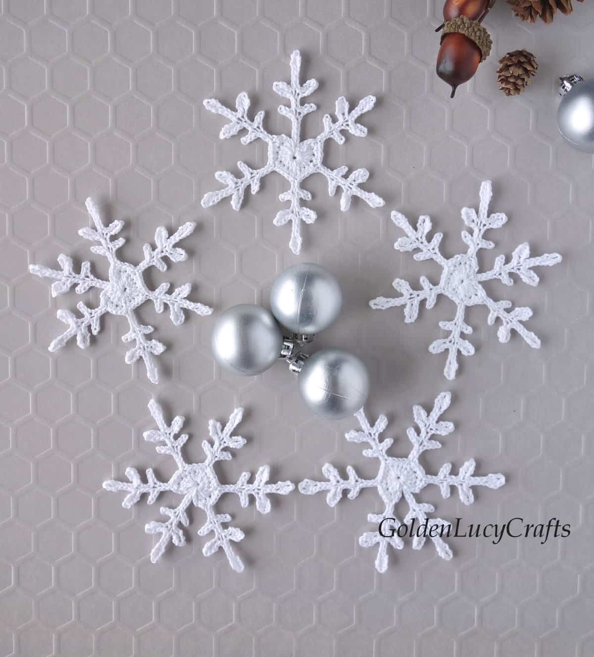 Crochet white snowflakes with heart center, small silver Christmas ball ornaments, small acorns and pinecones.