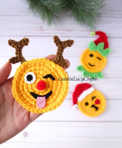 Crochet reindeer emoji in the palm of a hand.