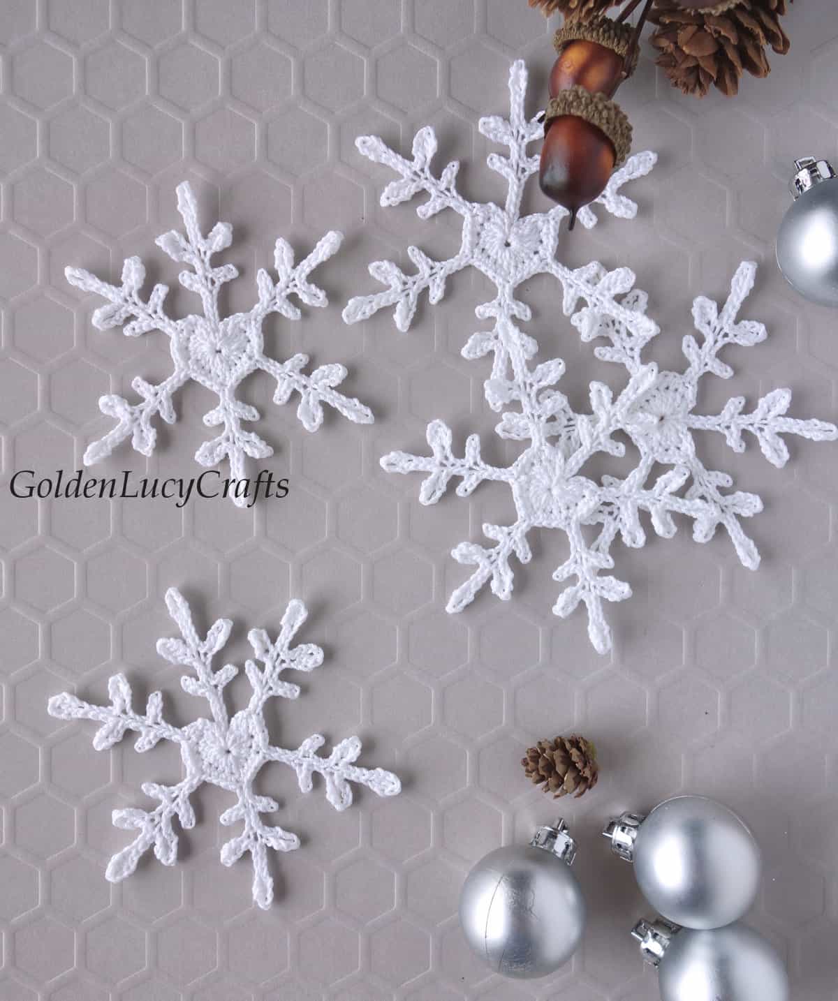 Crochet white snowflakes with heart center, small silver Christmas ball ornaments, small acorns and pinecones