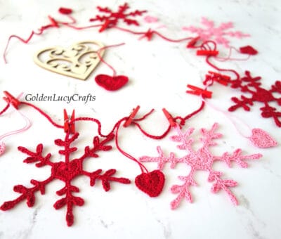 Crochet Valentines Day garland made from snowflakes and hearts in red and pink colors.