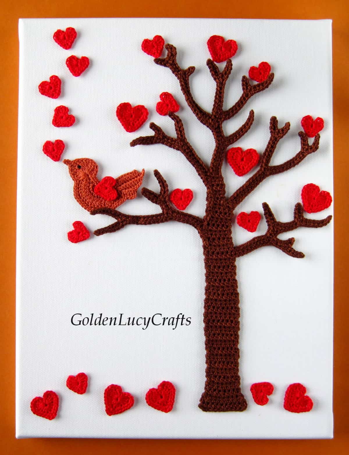 Crocheted applique tree with hearts and bird on it.