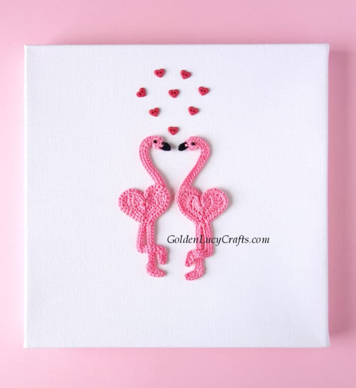 Valentine's Day wall art - two crocheted flamingo applique and small heart-shaped buttons above them.