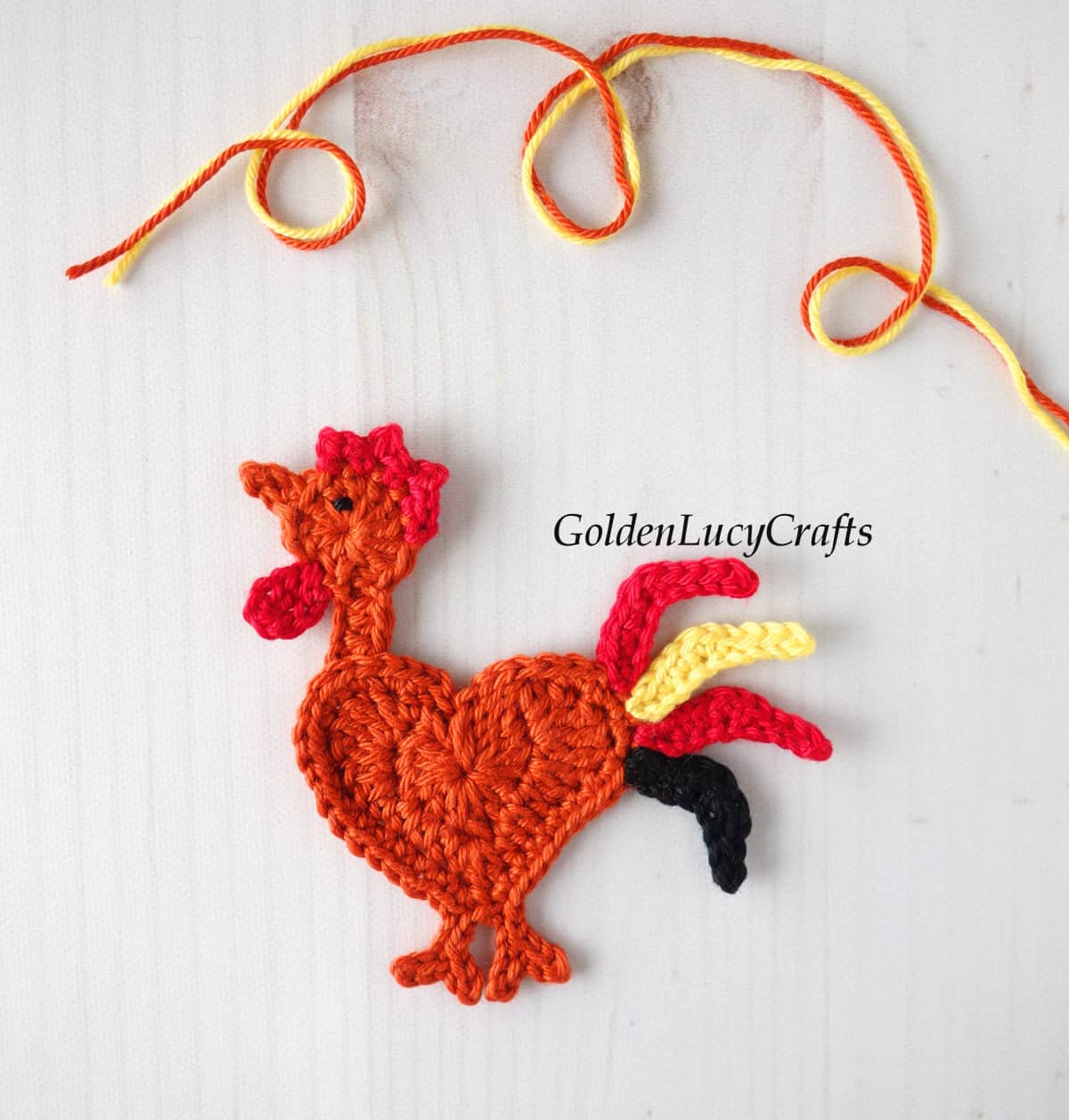 Crocheted rooster applique in dark orange color.