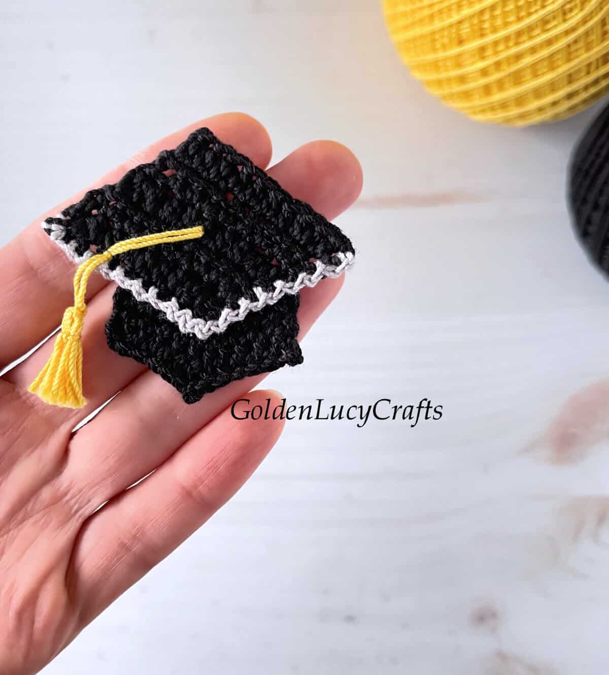 Crochet graduation cap applique in the palm of a hand.