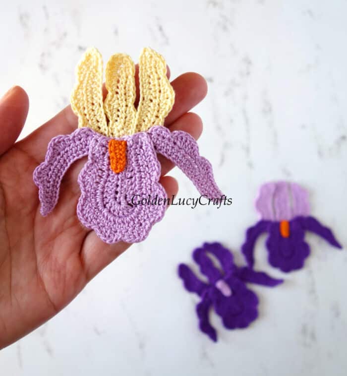 Crochet iris applique in the palm of a hand.