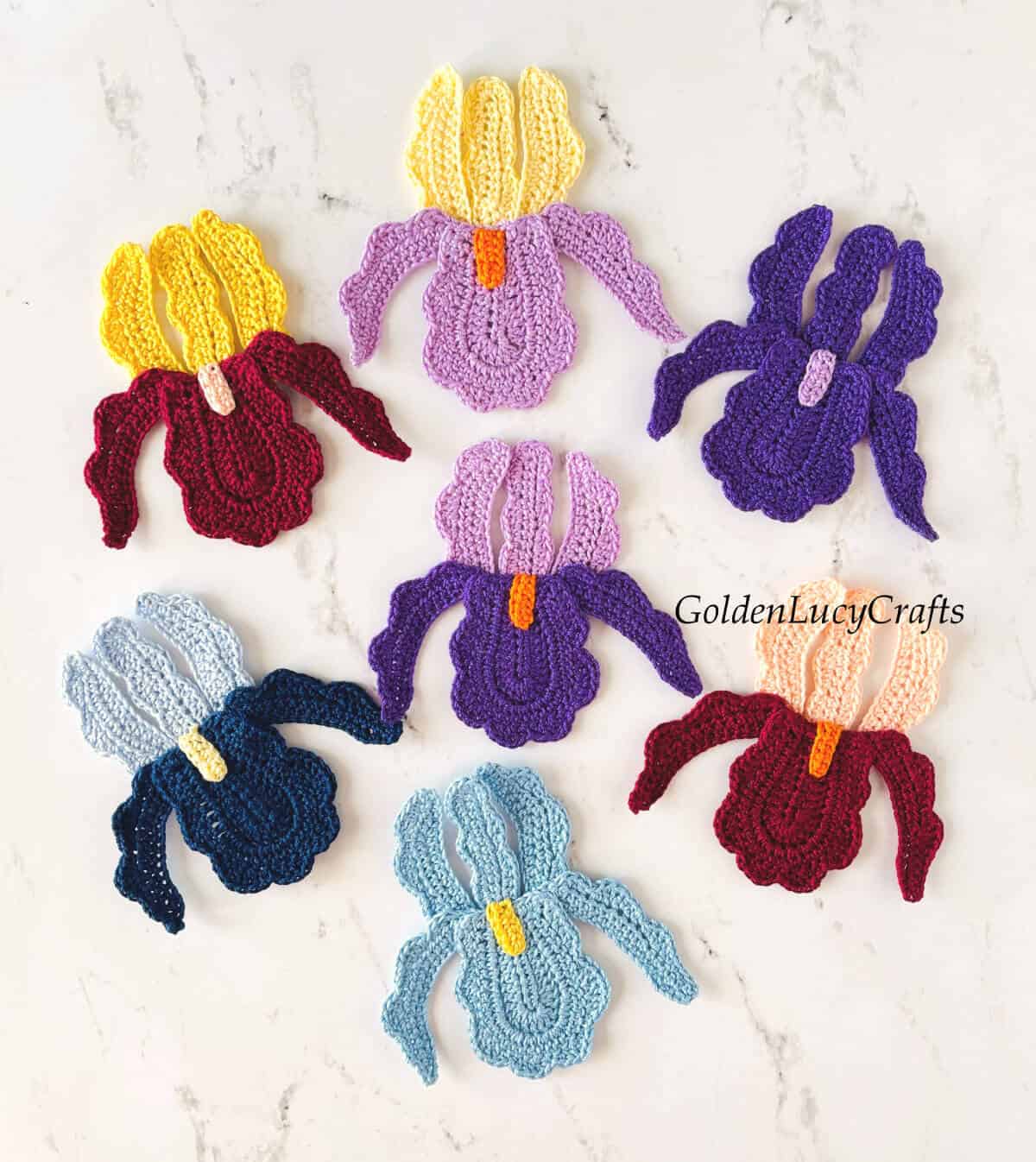 Seven crocheted iris appliques in different colors.