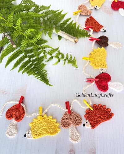 Crocheted mushrooms and hedgehogs attached with clothespins to the string.