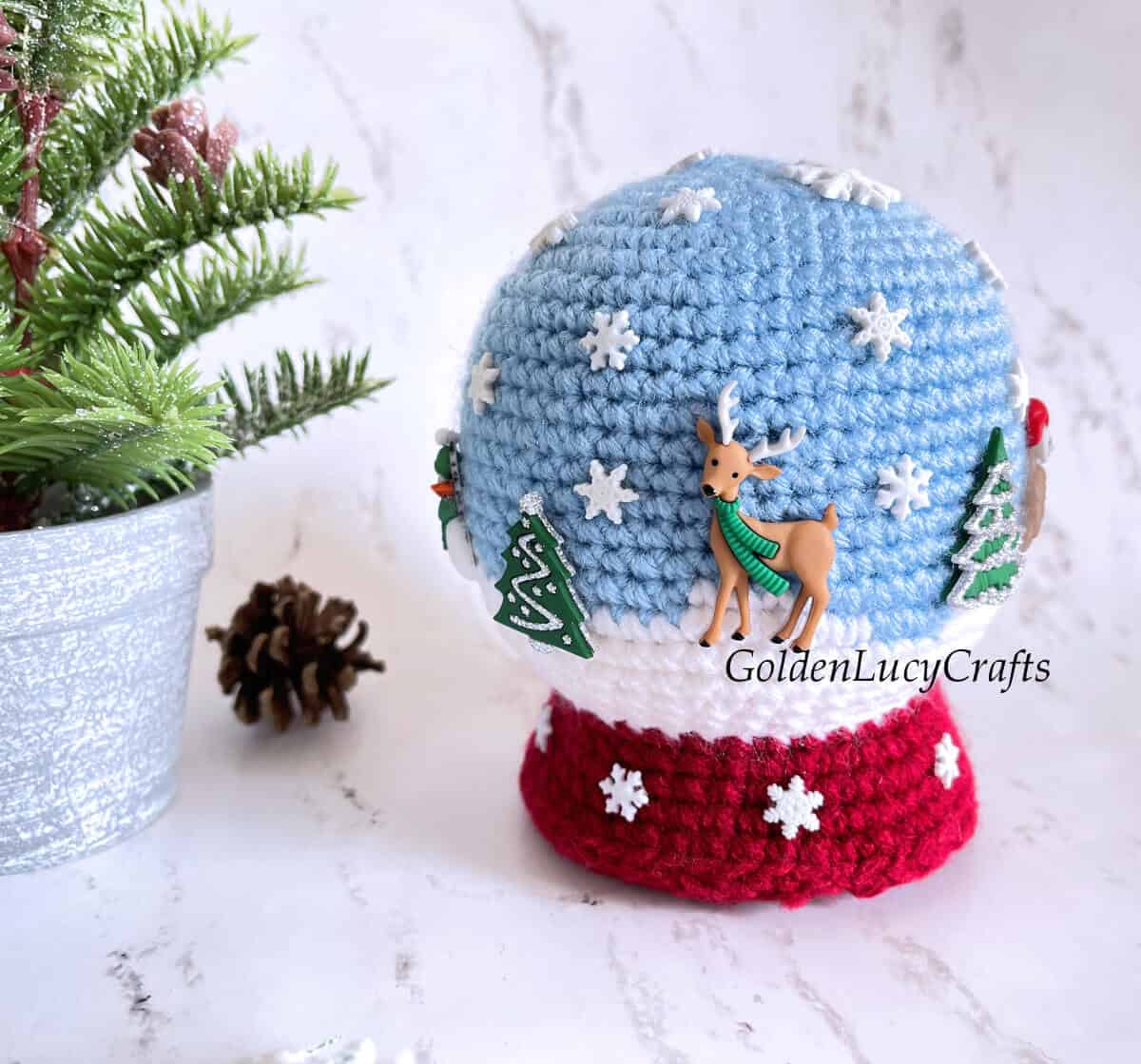 Crocheted snowglobe toy embellished with winter-themed buttons.
