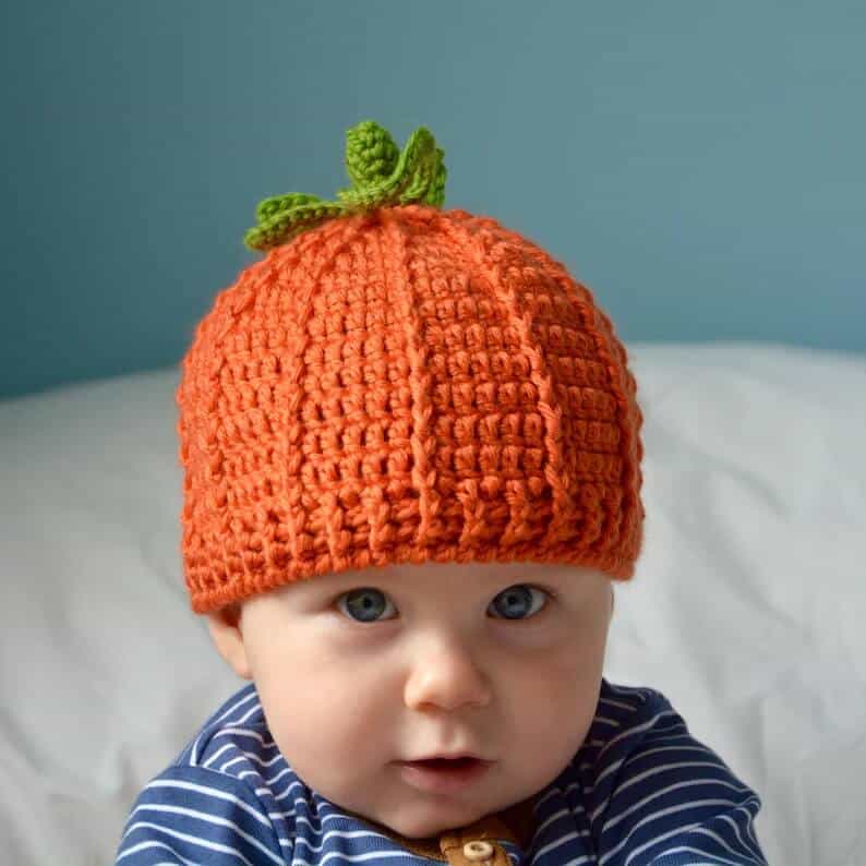 Baby dressed in crochet pumpkin hat.