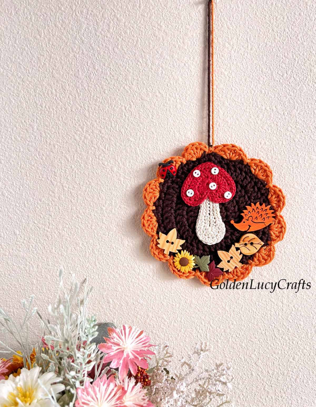 Crocheted Fall themed ornament hanging on the wall.