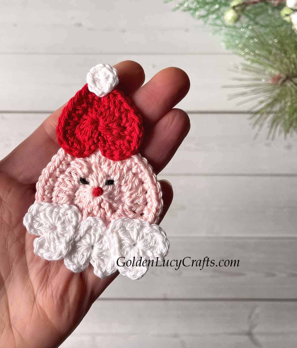 Crocheted Santa ornament is the palm of a hand.