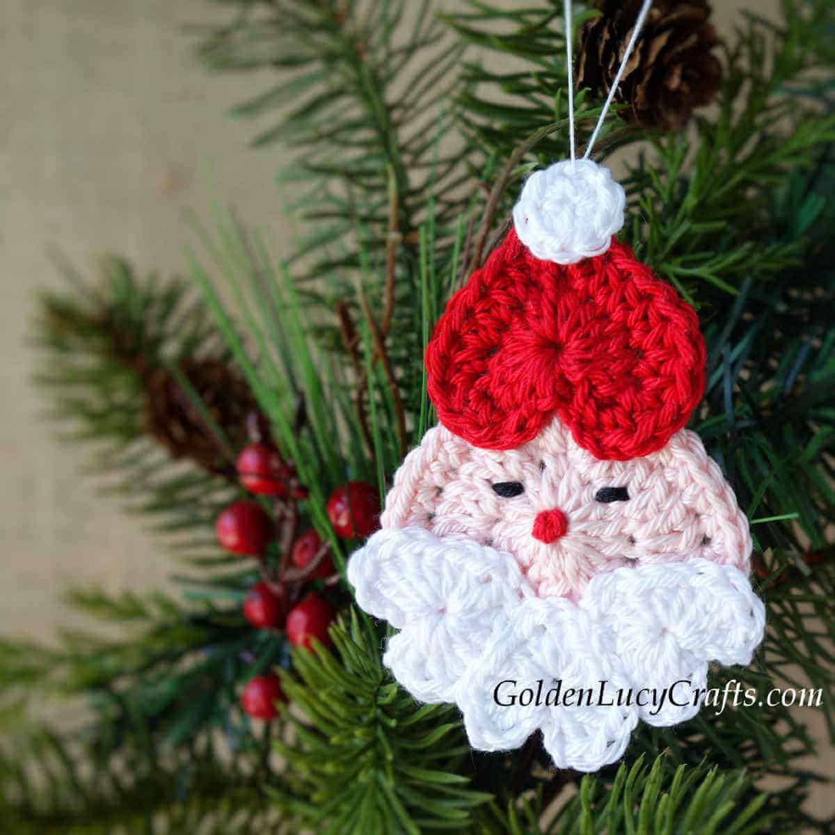 Crochet heart Santa ornament hanging on a Christmas tree.