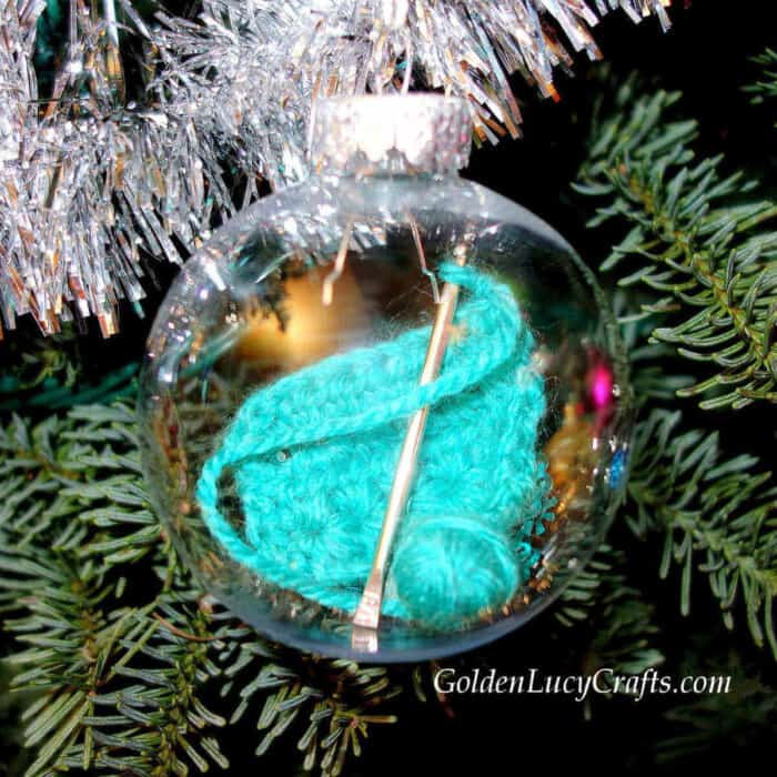 Clear ball Christmas ornament with crochet hook, small ball of yarn and crochet swatch inside.