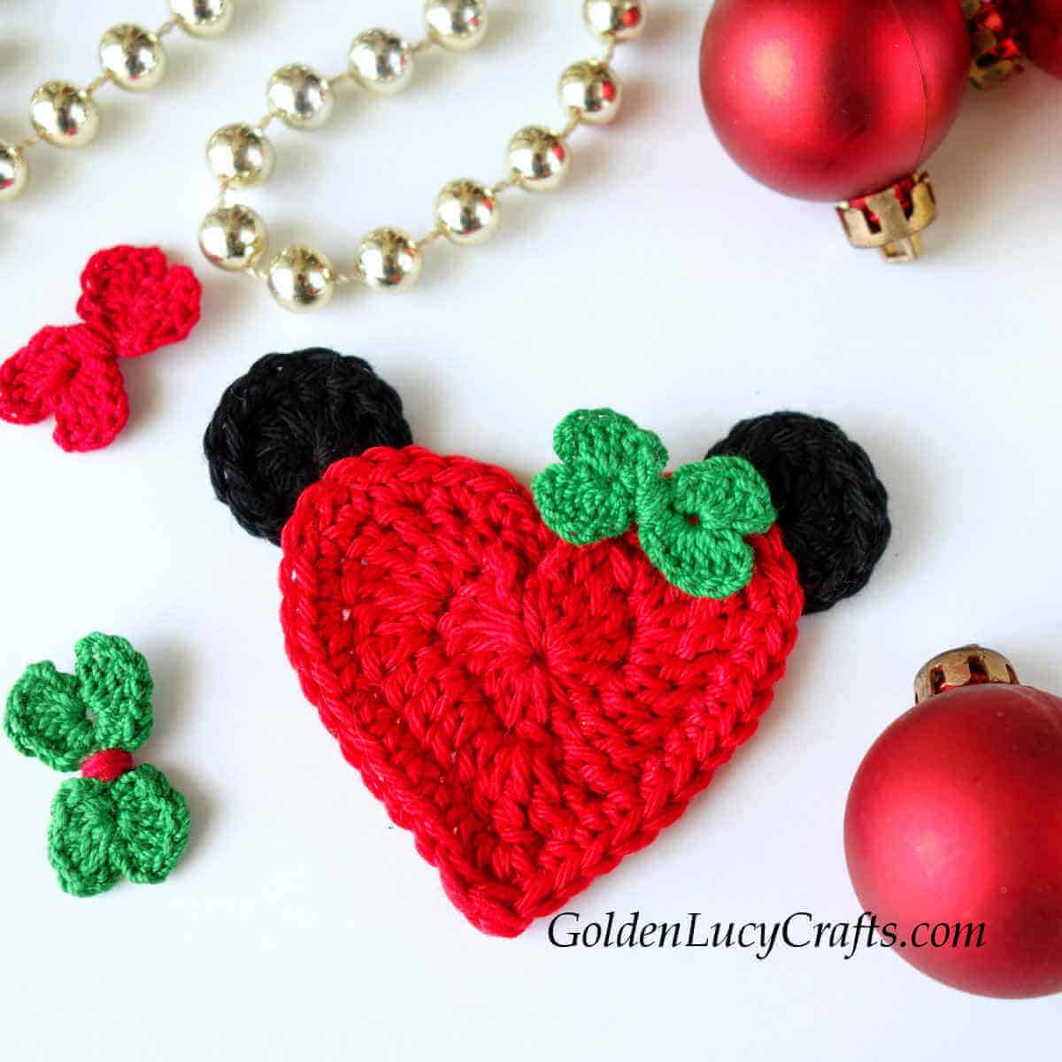 Crocheted red hear with black ears and green bow.